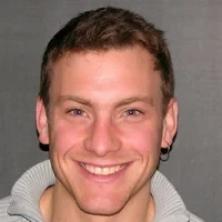 Eine Wissenschaftlerin und ein Wissenschaftler arbeiten hinter einer Glasfassade und mischen Chemikalien mit Großgeräten.